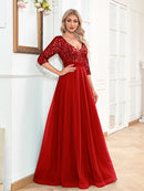 Woman wearing a red evening gown with sequin details in a room.
