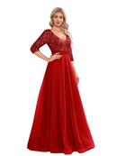 Woman wearing a red evening gown with lace detailing in a room.