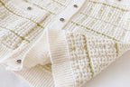 Close-up of a textured white fabric with gold accents on a white background