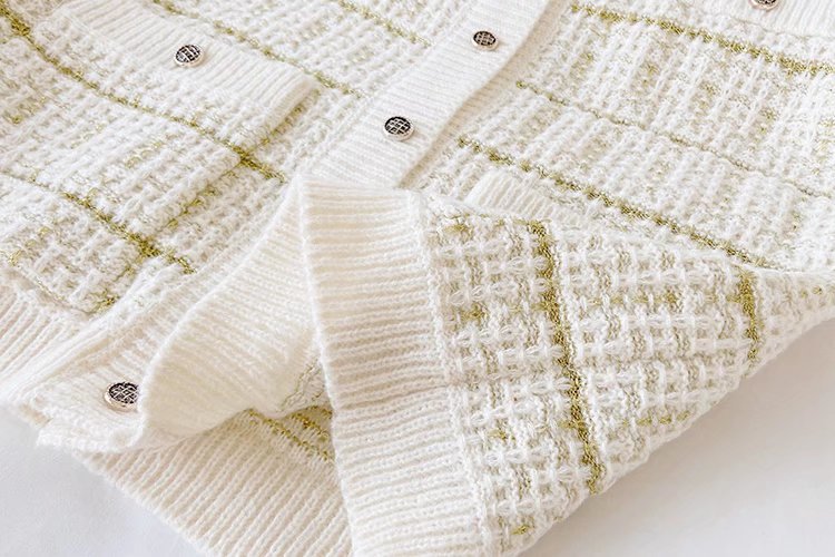 Close-up of a textured white fabric with gold accents on a white background