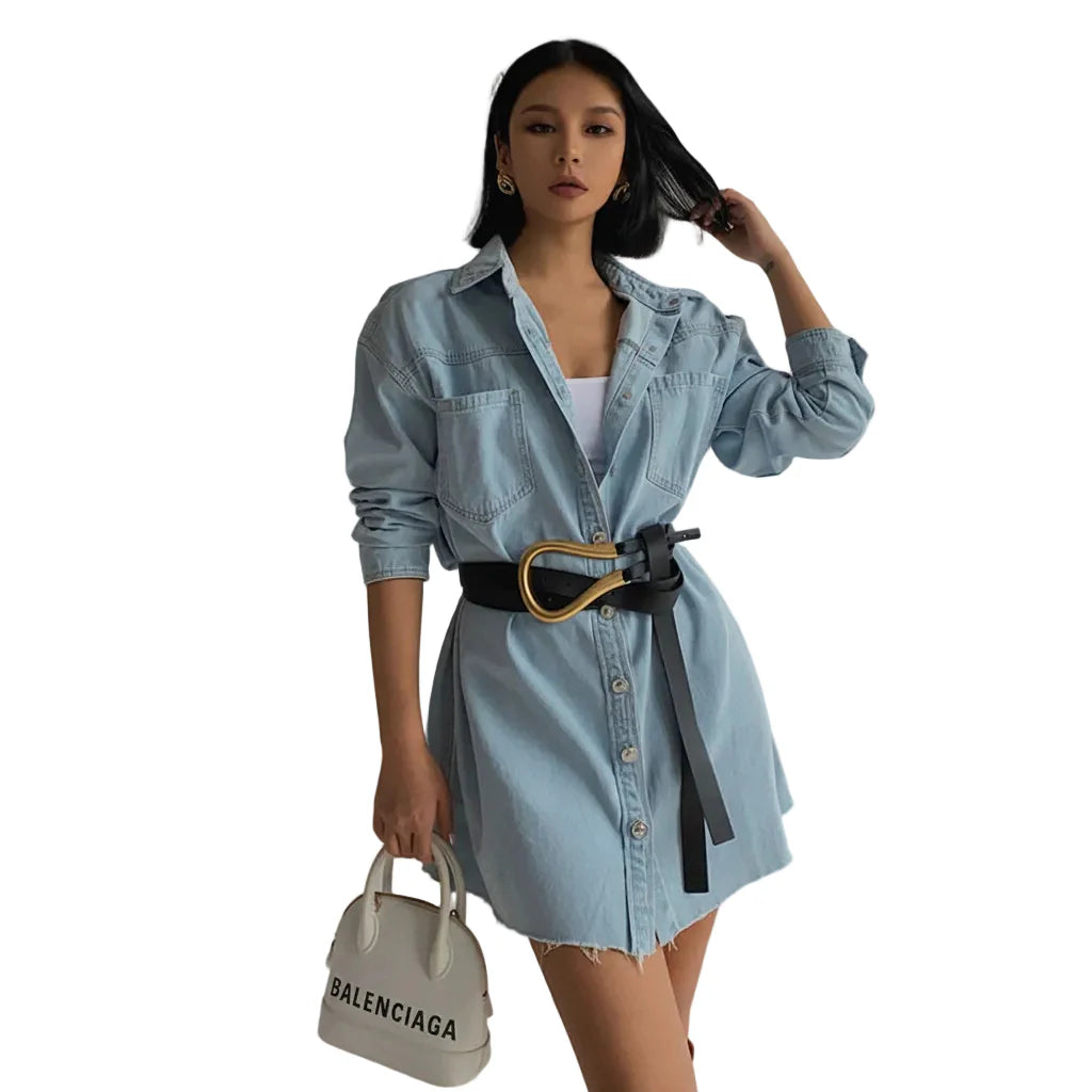 Woman wearing a denim dress with a Balenciaga handbag on a white background