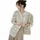 Woman wearing a light-colored textured jacket with a blurred indoor background