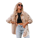 Woman wearing a beige jacket, black top, and light blue jeans on a city street.