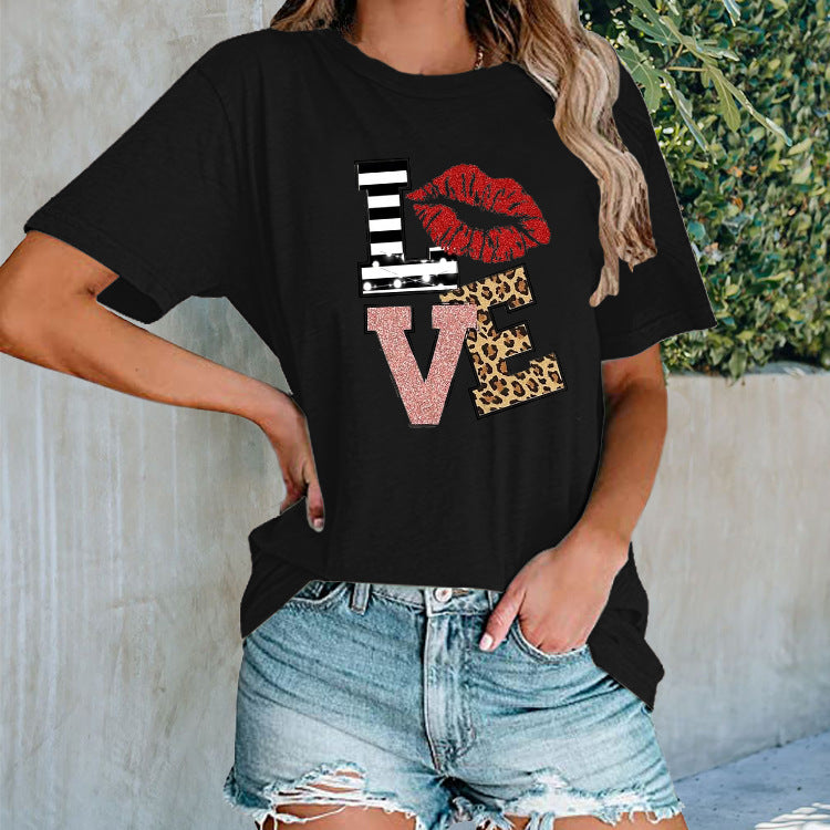 Person wearing a black t-shirt with colorful 'LOVE' graphic design outdoors.