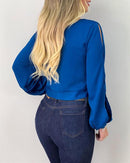 Person wearing a blue top and dark jeans against a plain background
