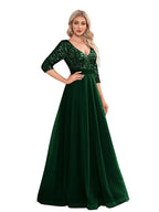 Woman wearing a green evening gown with sequin detailing in a room.