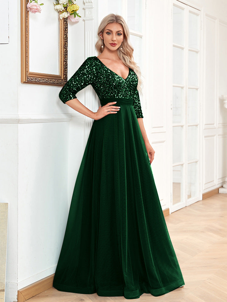 Woman wearing a green evening gown with sequin detailing in a room.