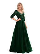 Woman wearing a green evening gown with sequin detailing in a room.