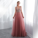 Woman wearing a pink evening gown with a beaded top in a bright room.