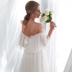 Woman in a white wedding dress holding flowers in a softly lit room.