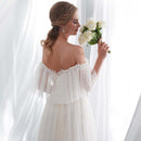 Woman in a white wedding dress holding flowers in a softly lit room.