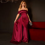 Woman in a burgundy evening gown holding a clutch in a dimly lit room.