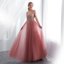 Pink evening gown with beaded top on a model against a white curtain background