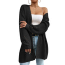 Person wearing a black cardigan over a white top and blue jeans against a white background
