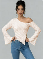 Woman wearing a white off-shoulder top and blue jeans against a gray background