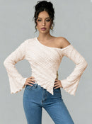 Woman wearing a white off-shoulder top and blue jeans against a gray background